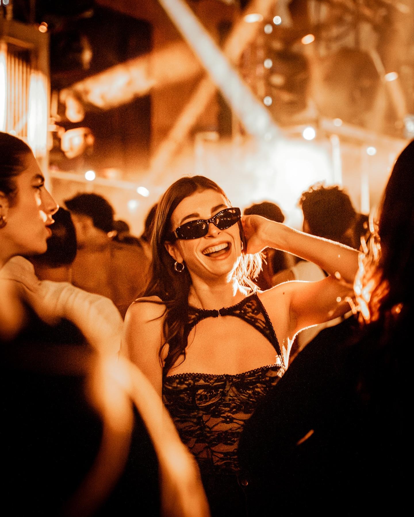 A laughing raver in sunglasses lit by golden stage light